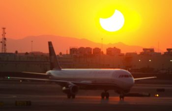 Solar eclipse as sun sets behind airplane at airport