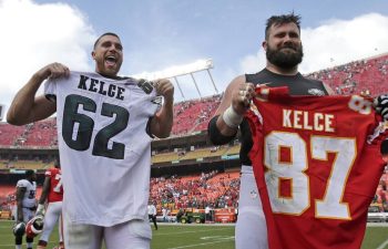 Travis and Jason Kelce hold eachother's football jerseys