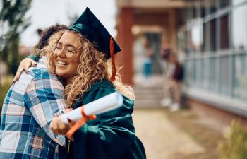 Happy graduate student embraces her father after graduation ceremony.