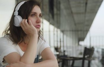 Woman listening to headphones, looking sad